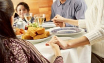 photograph of family holding hands around dinner table